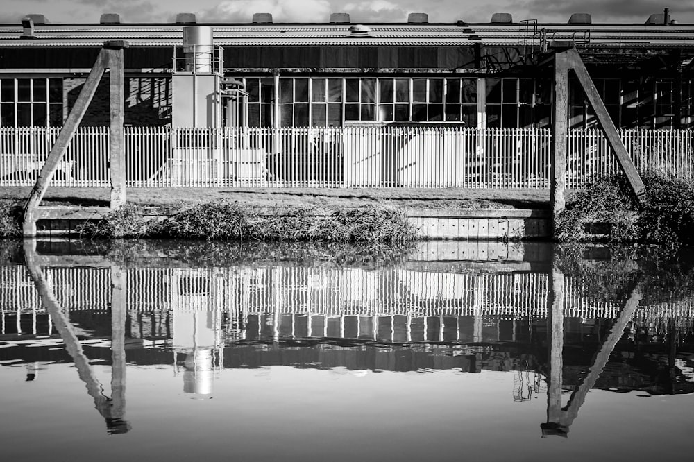 a black and white photo of a fenced in area next to a body of