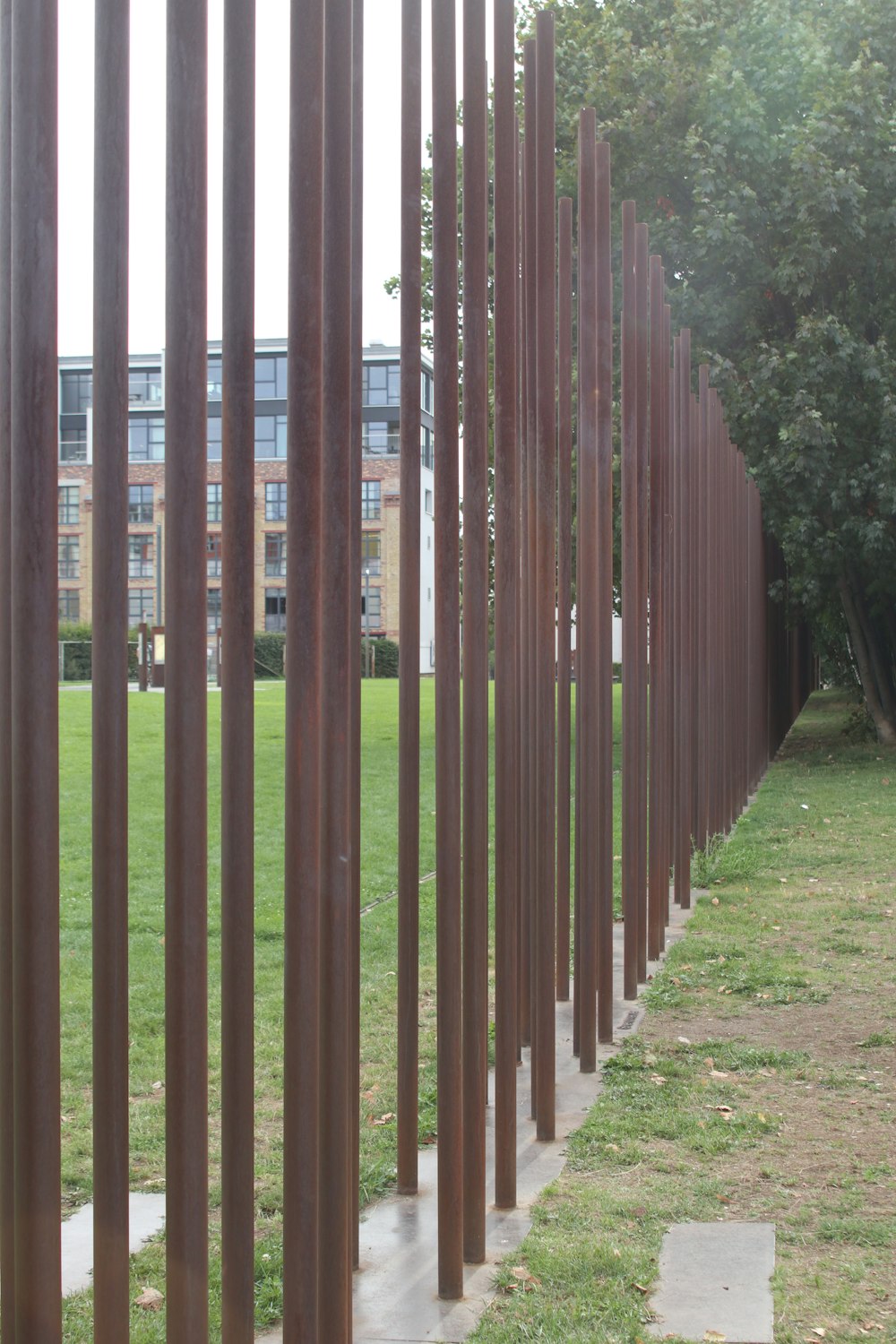 a row of metal poles sitting next to a lush green park