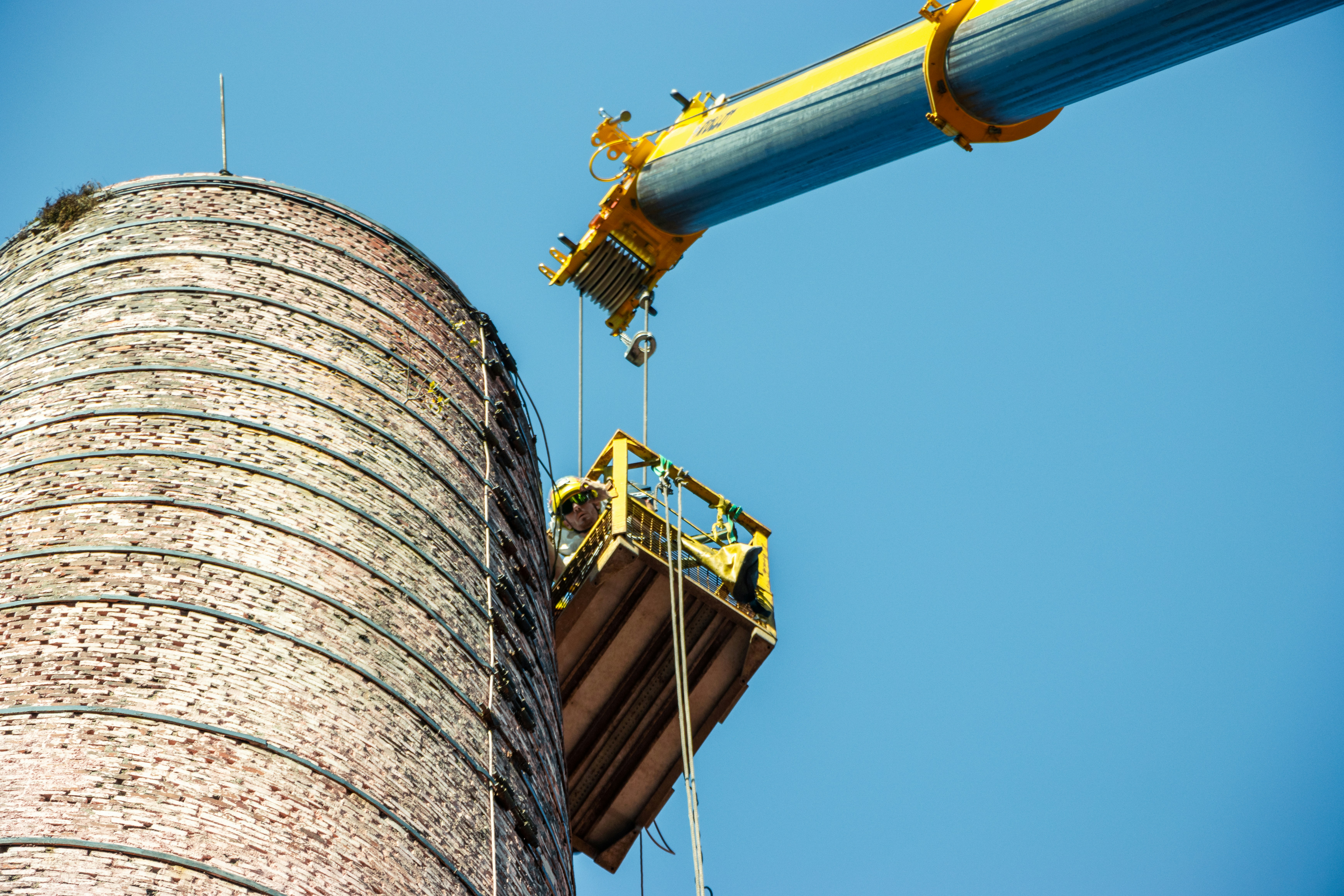 a man on a crane working on a brick tower