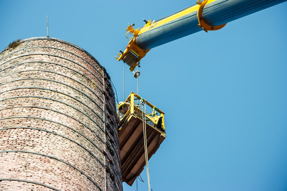 a man on a crane working on a brick tower