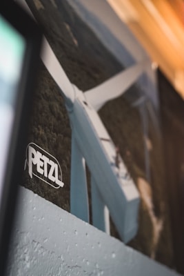 A close-up view of a wind turbine with three blades set against a forested background. The PETZL logo is visible in the foreground.
