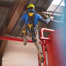 a man in safety gear climbing up a red railing