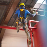 a man in safety gear climbing up a red railing