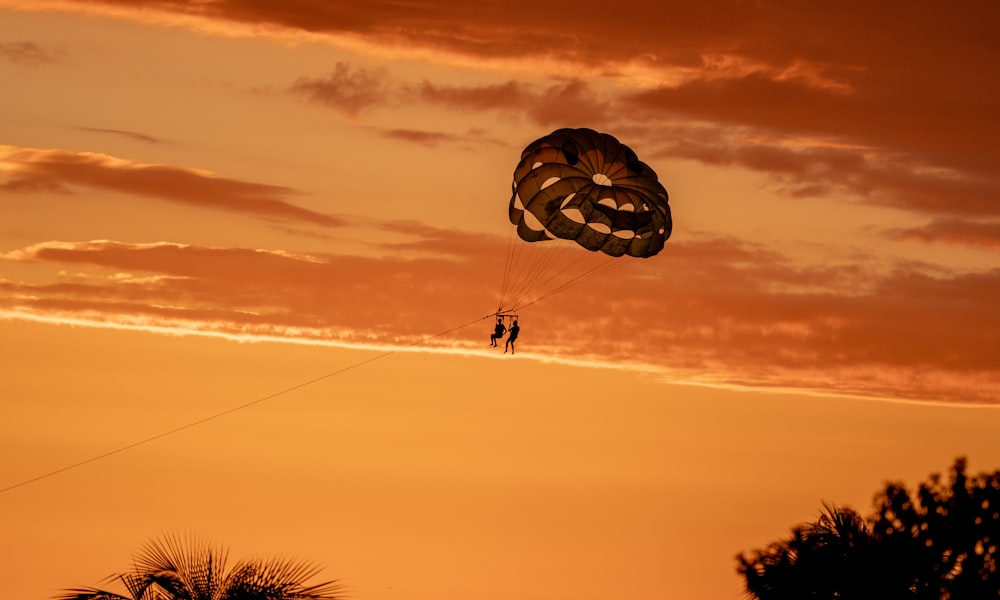 a person is parasailing in the sky at sunset