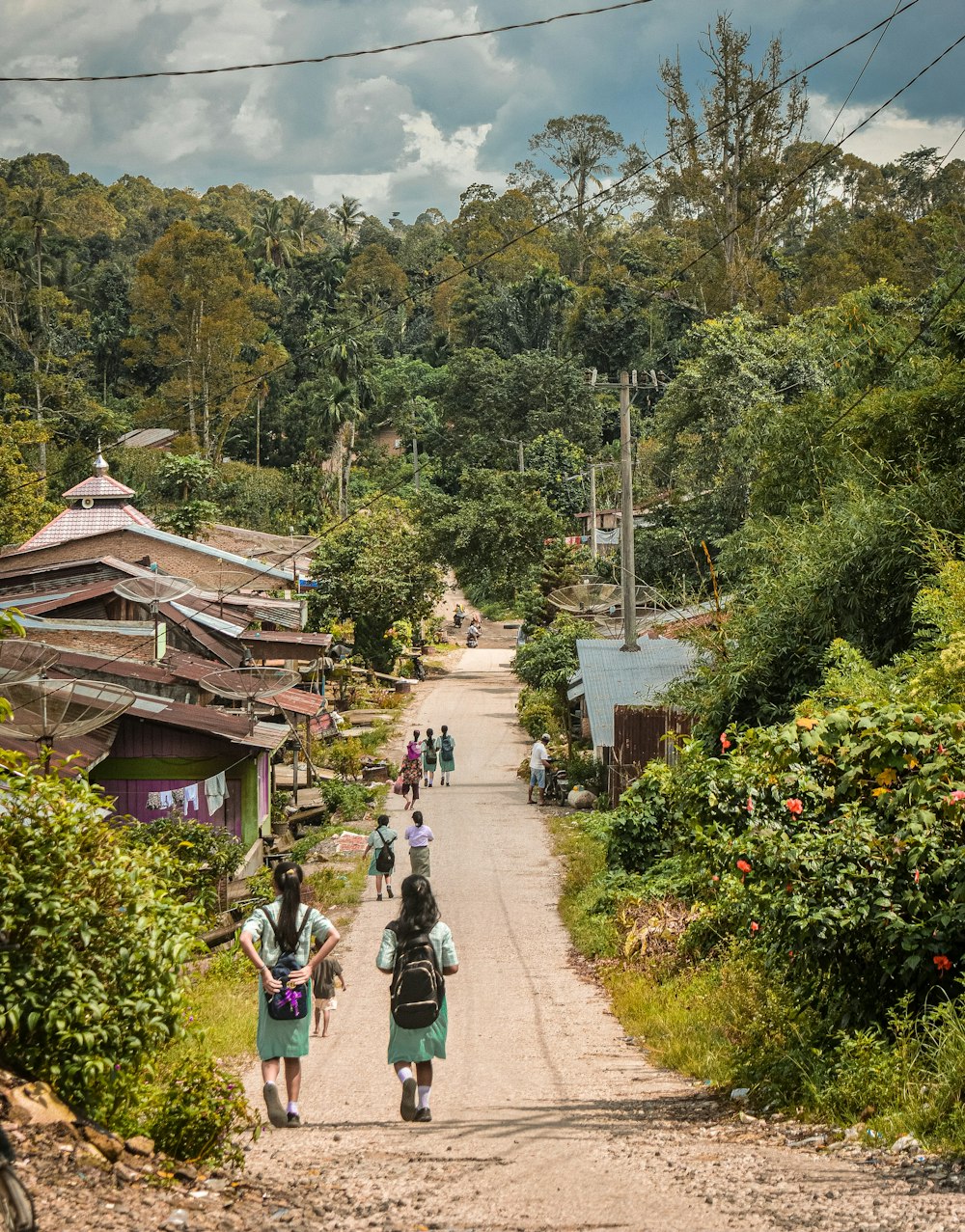 a group of people walking down a dirt road