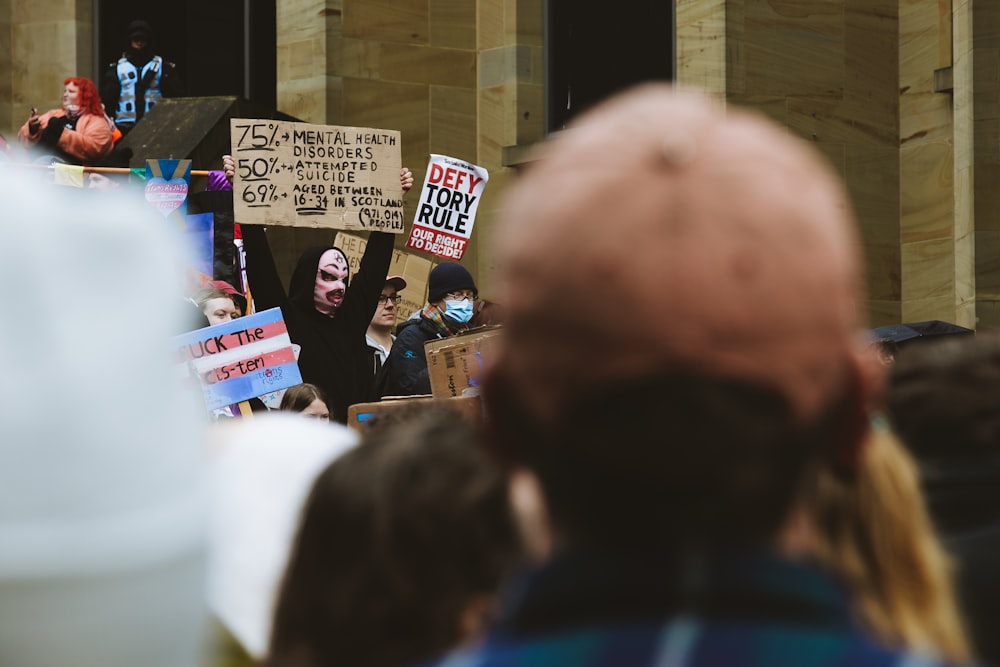 a crowd of people holding signs and wearing masks