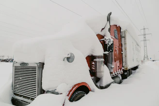 Fuel delivery truck refueling a stranded vehicle on a snowy Buffalo highway.