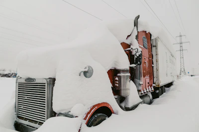 Fuel delivery truck refueling a stranded vehicle on a snowy Buffalo highway.