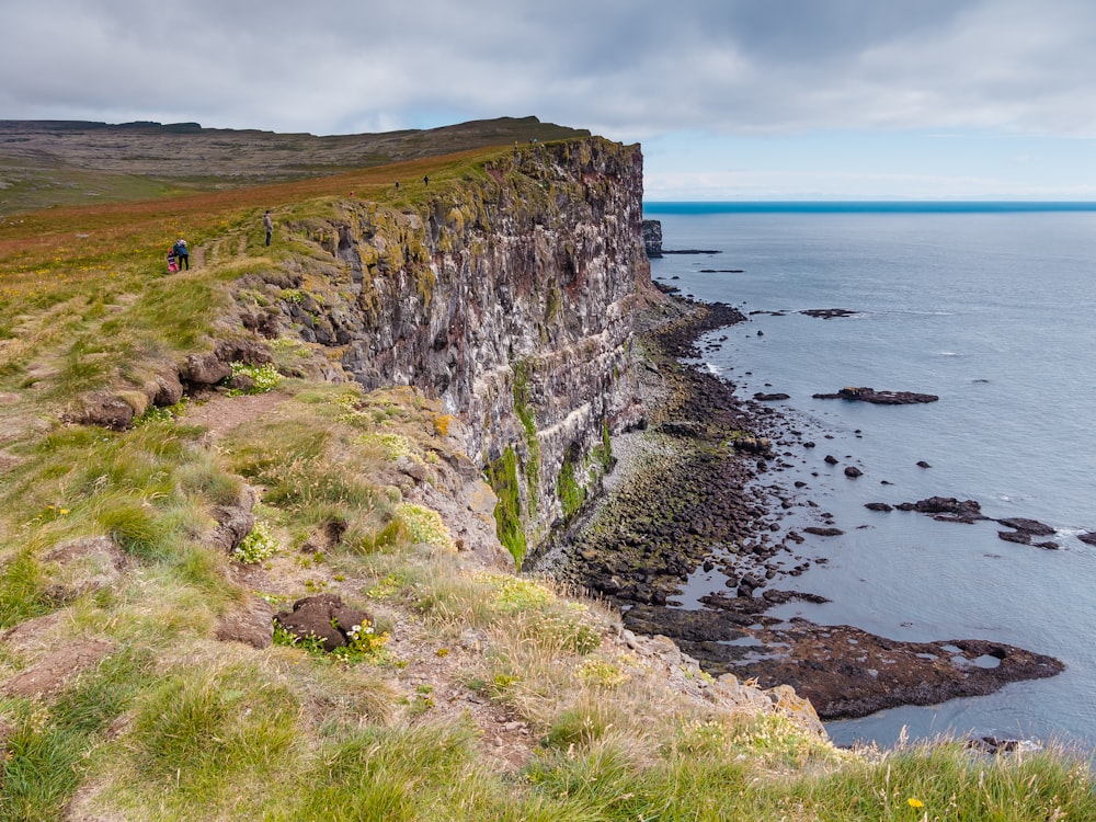 a man standing on the edge of a cliff next to the ocean