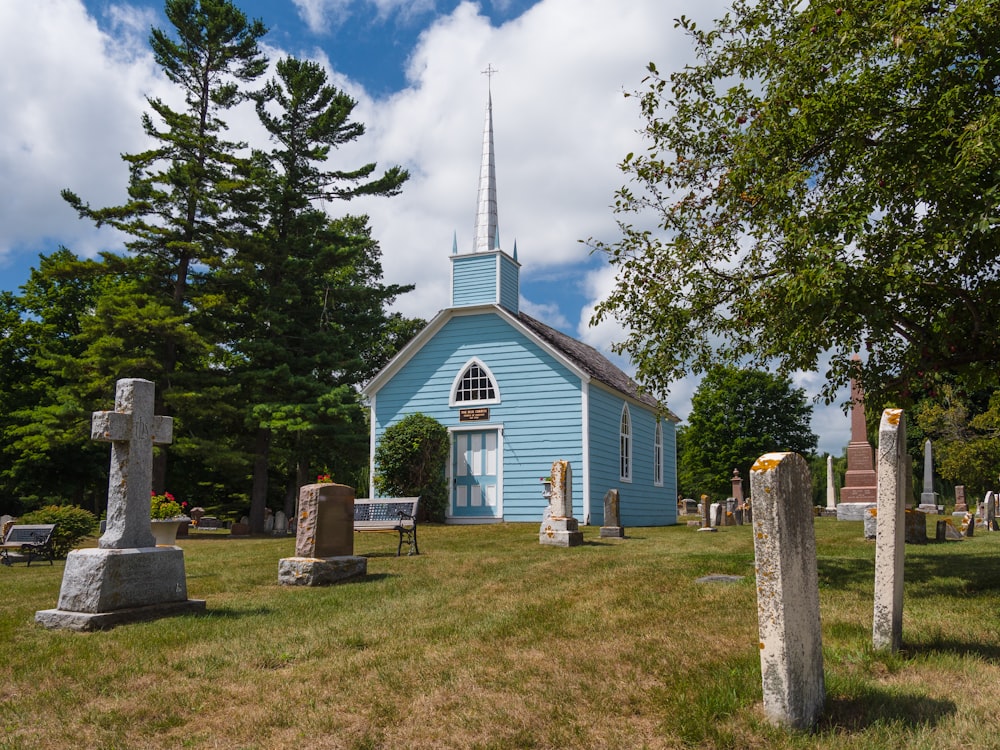 a blue church with a steeple surrounded by trees