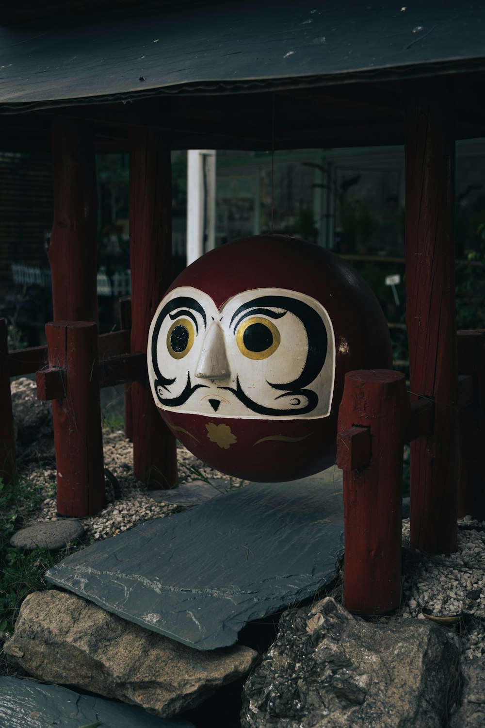 a red and white mask sitting on top of a rock