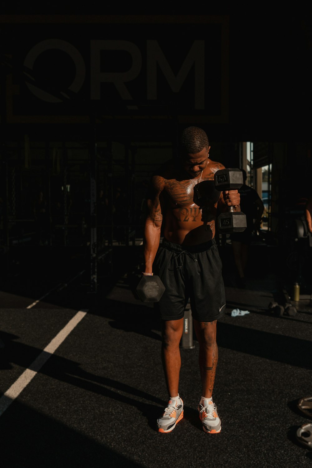 a shirtless man holding a dumbbell in the dark