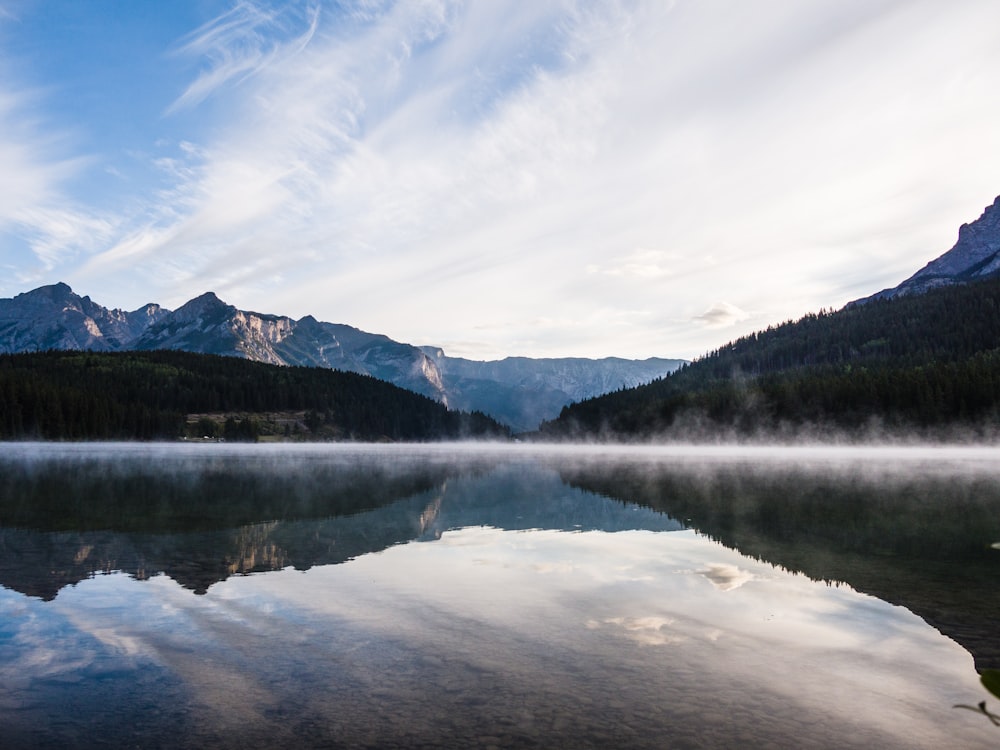 a body of water surrounded by mountains and clouds