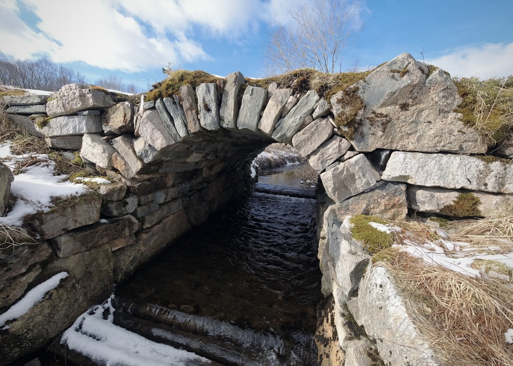 a stone bridge over a small stream in the snow