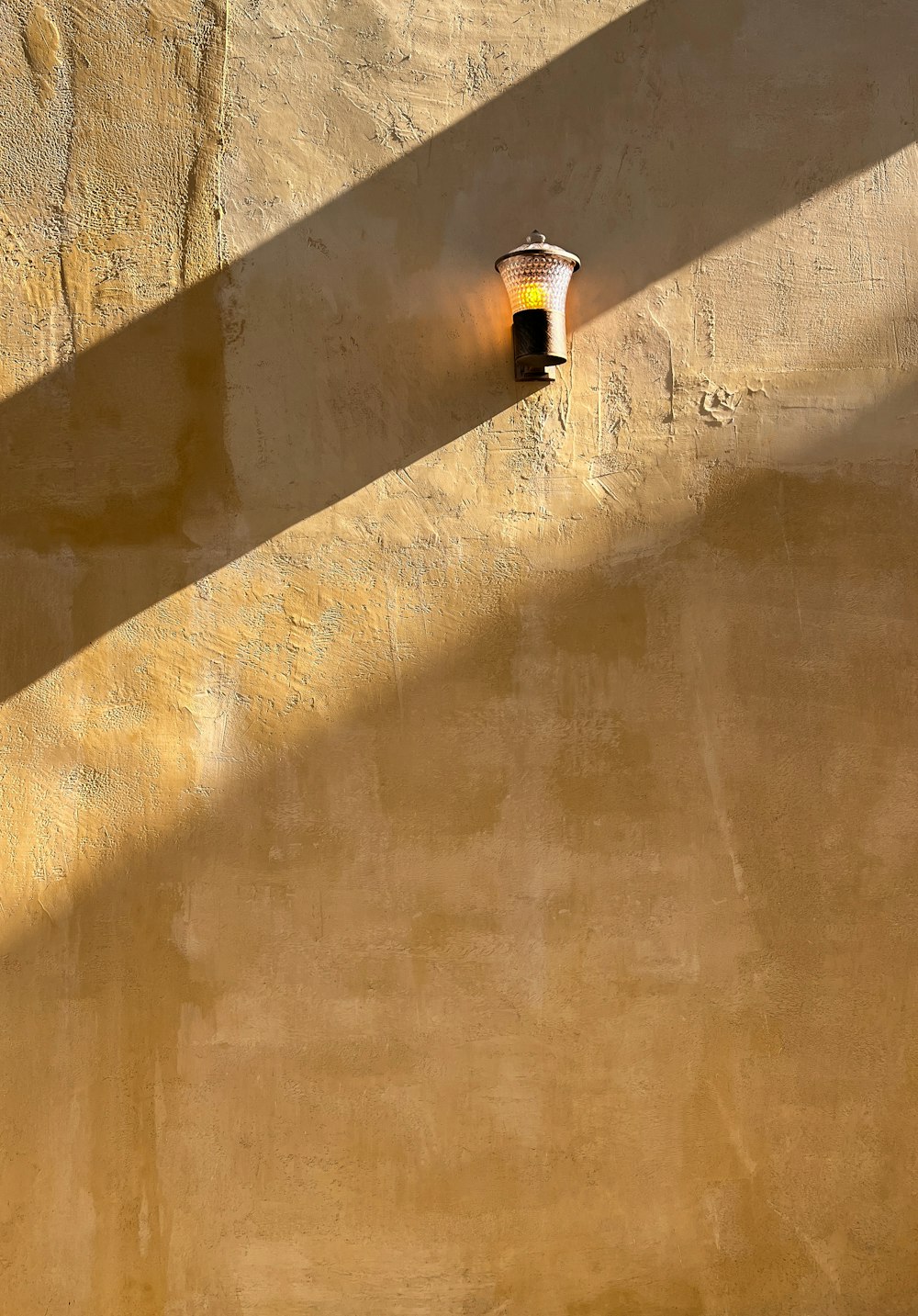 a wall with a lamp on it and a shadow on the wall