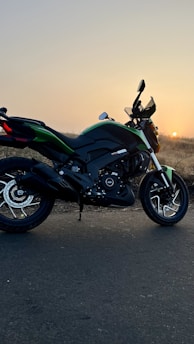 A stylish motorcycle parked on a scenic mountain road during sunset.