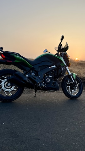 A sleek Saki Motors electric motorcycle parked by a scenic riverside road during sunset.