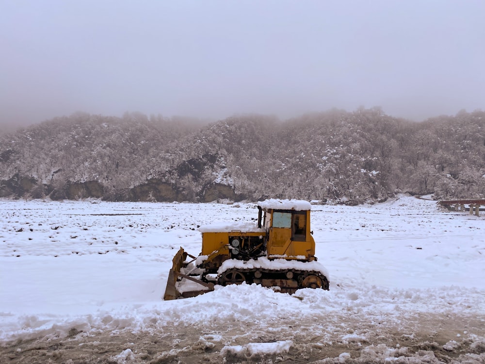 a bulldozer sits in the middle of a snowy field
