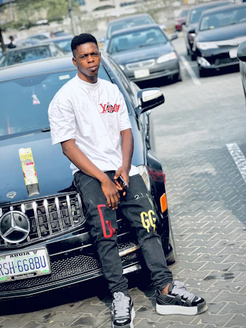 A young entrepreneur smiling confidently while holding a football and a smart car gadget.