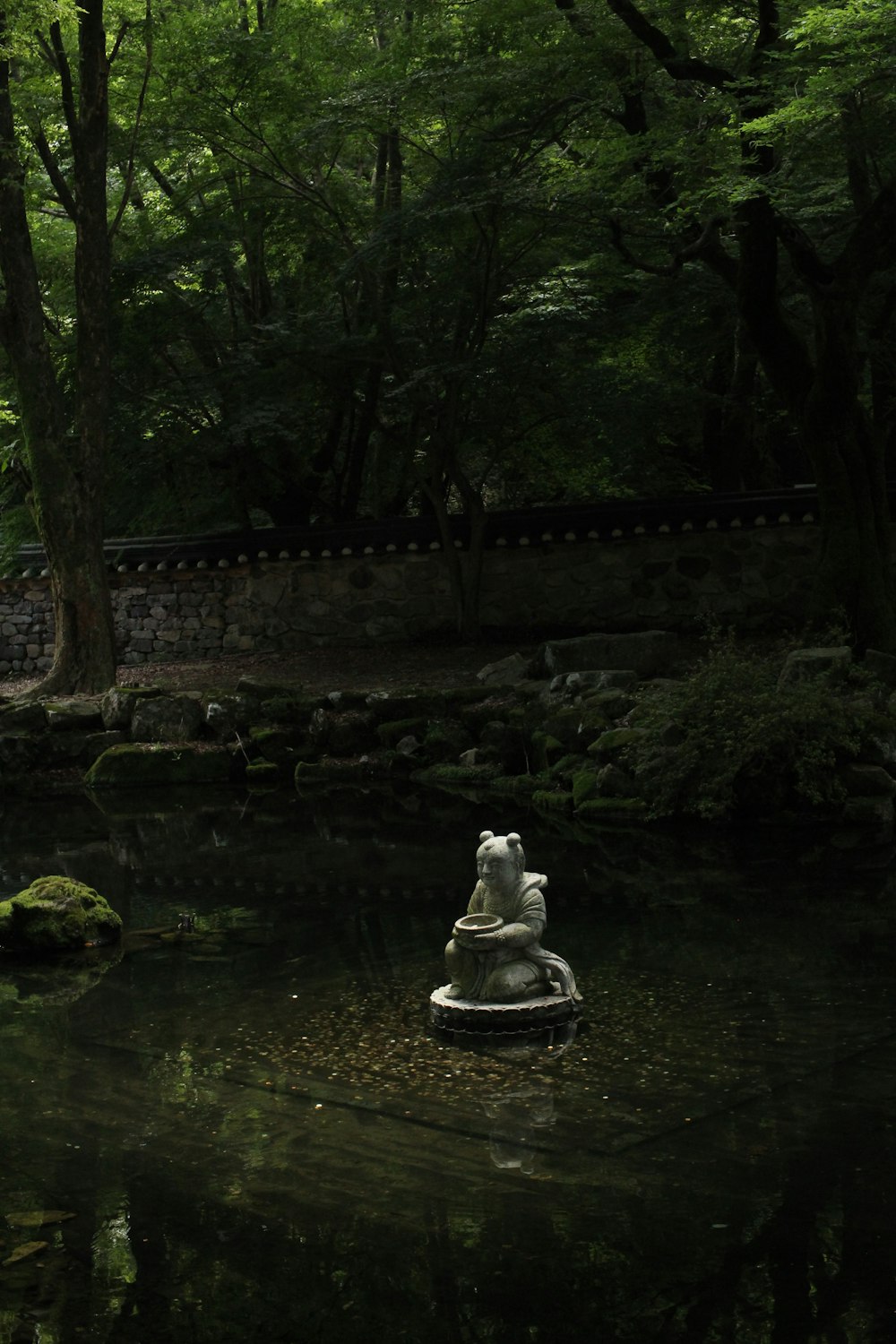 a statue in the middle of a small pond