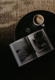 A snapshot of a café table with a latte, open book, and a Polaroid photo pinned to a corkboard.