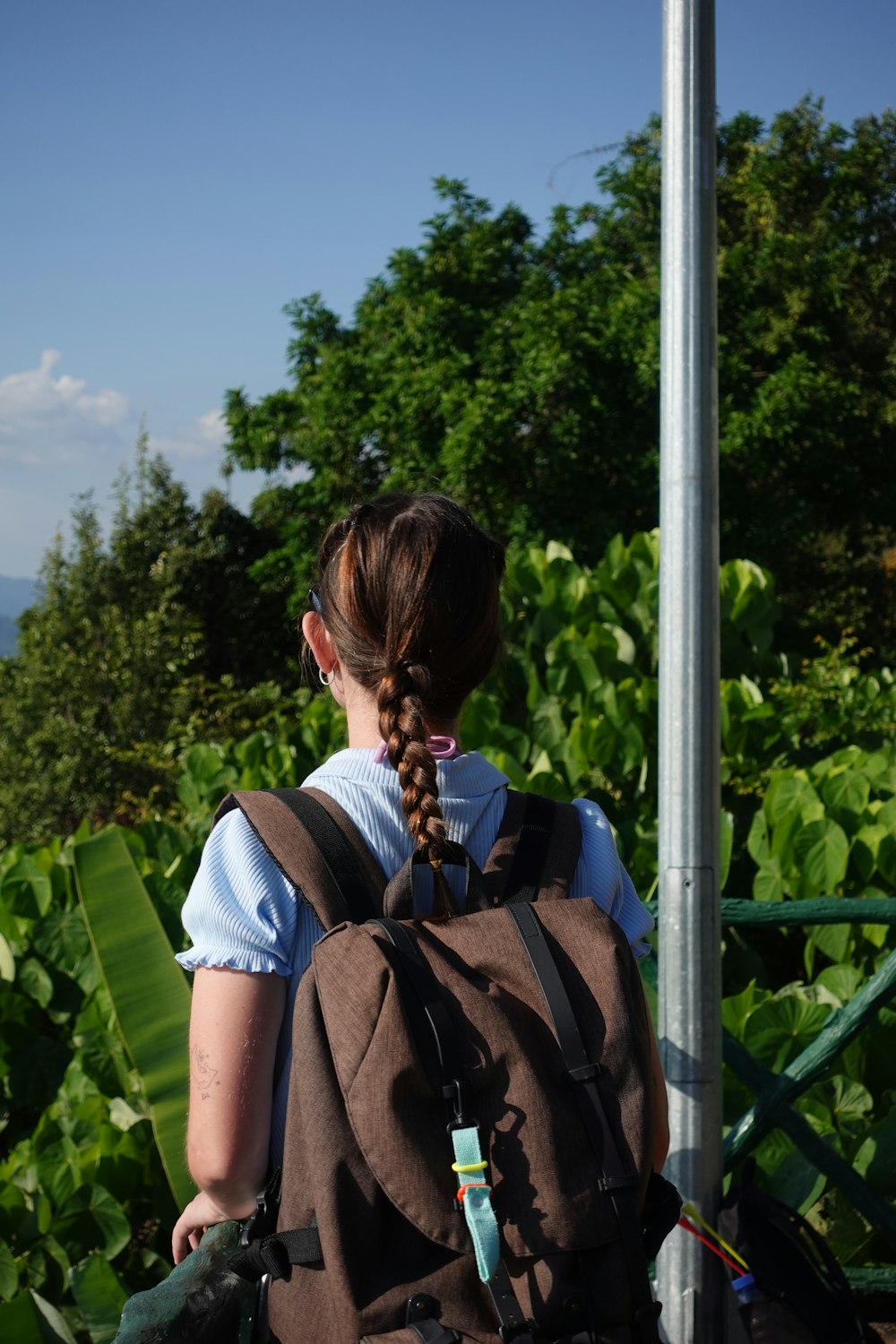 a woman with a backpack is standing by a pole