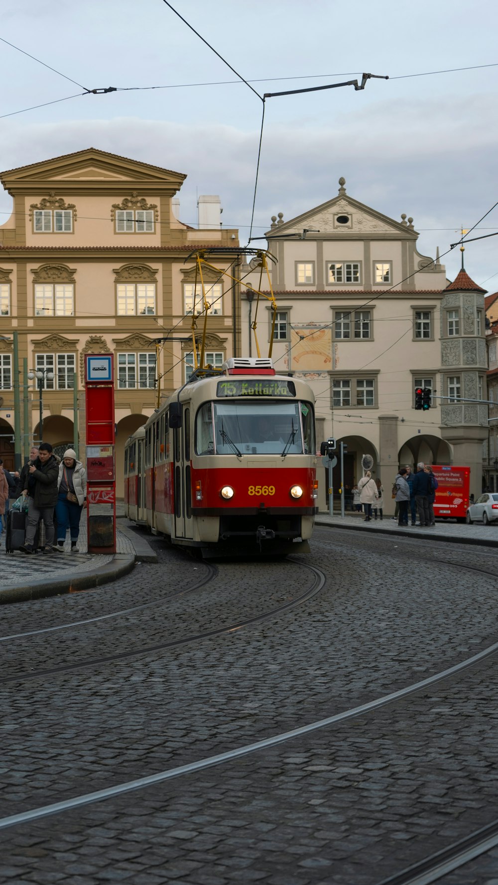 a red and white train traveling down a street next to tall buildings