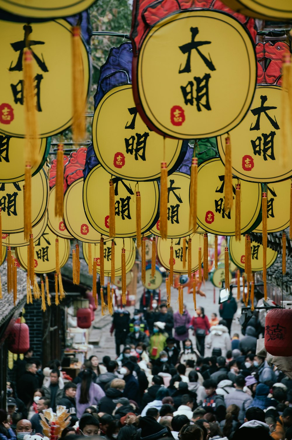 a crowd of people walking down a street next to yellow signs
