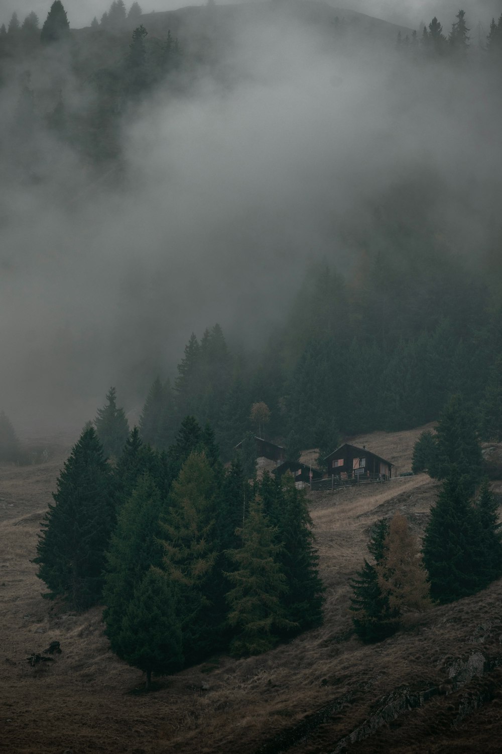 a foggy mountain with a small cabin in the foreground