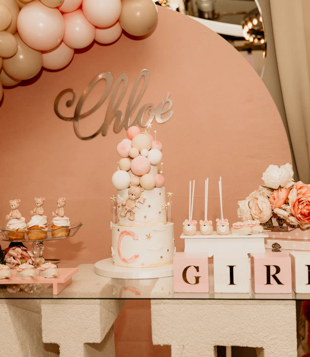 A colorful gift basket filled with balloons, plush toys, and personalized name tags arranged for a baby shower.