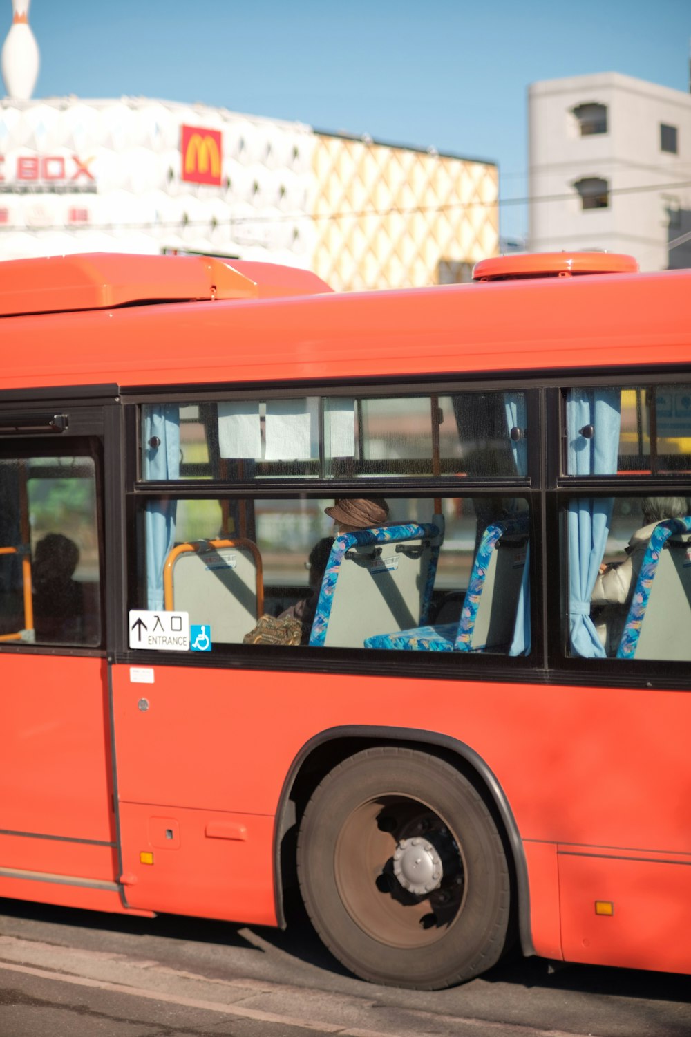 a red bus driving down a street next to tall buildings