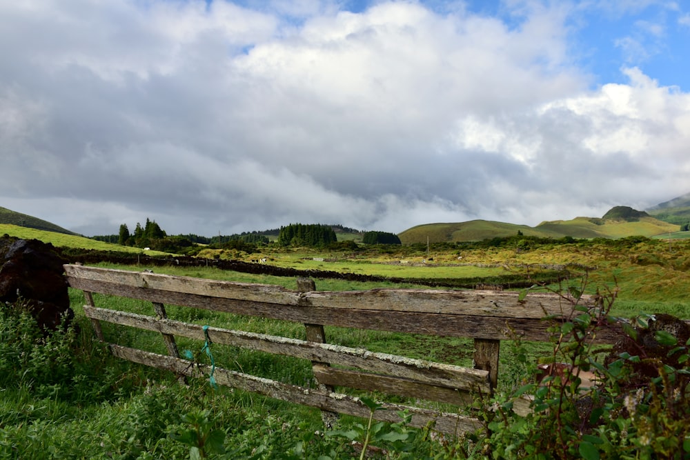 a wooden fence in the middle of a lush green field