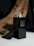 Close-up of a sleek cologne bottle with a subtle mist around it on a dark background.