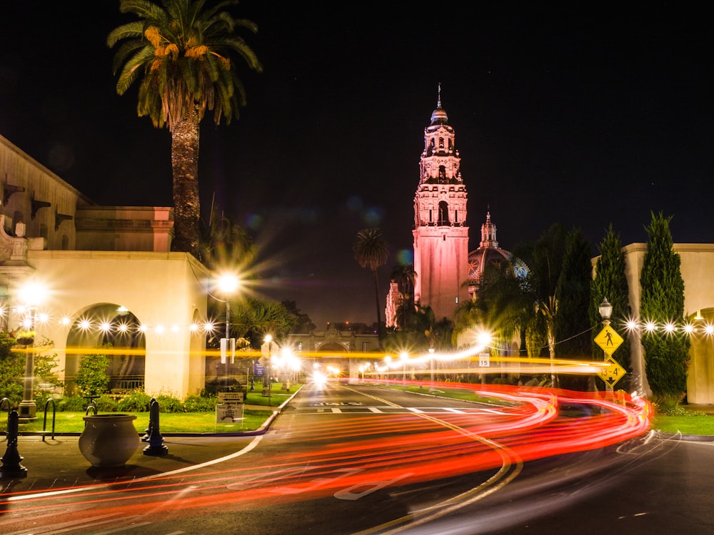 a city street at night with a clock tower in the background