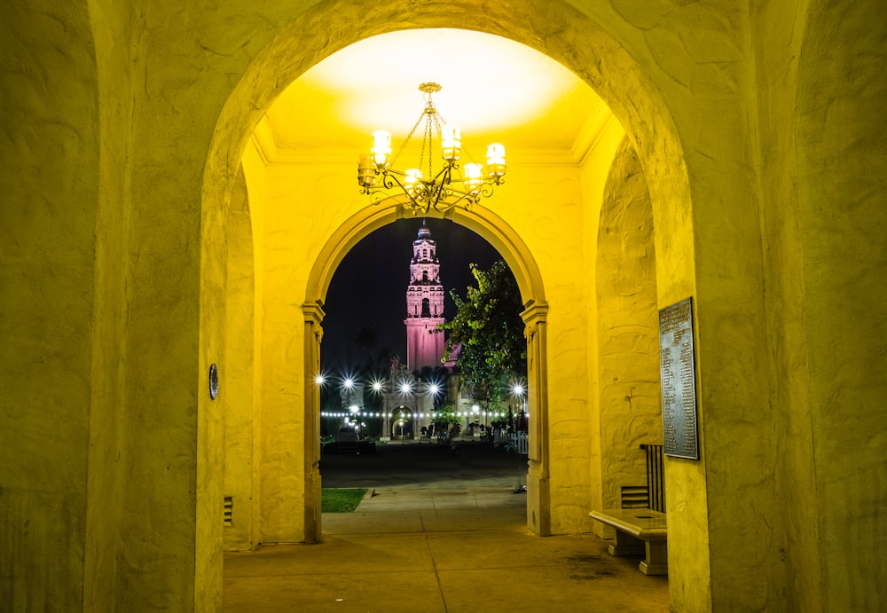 a yellow archway with a clock tower in the background