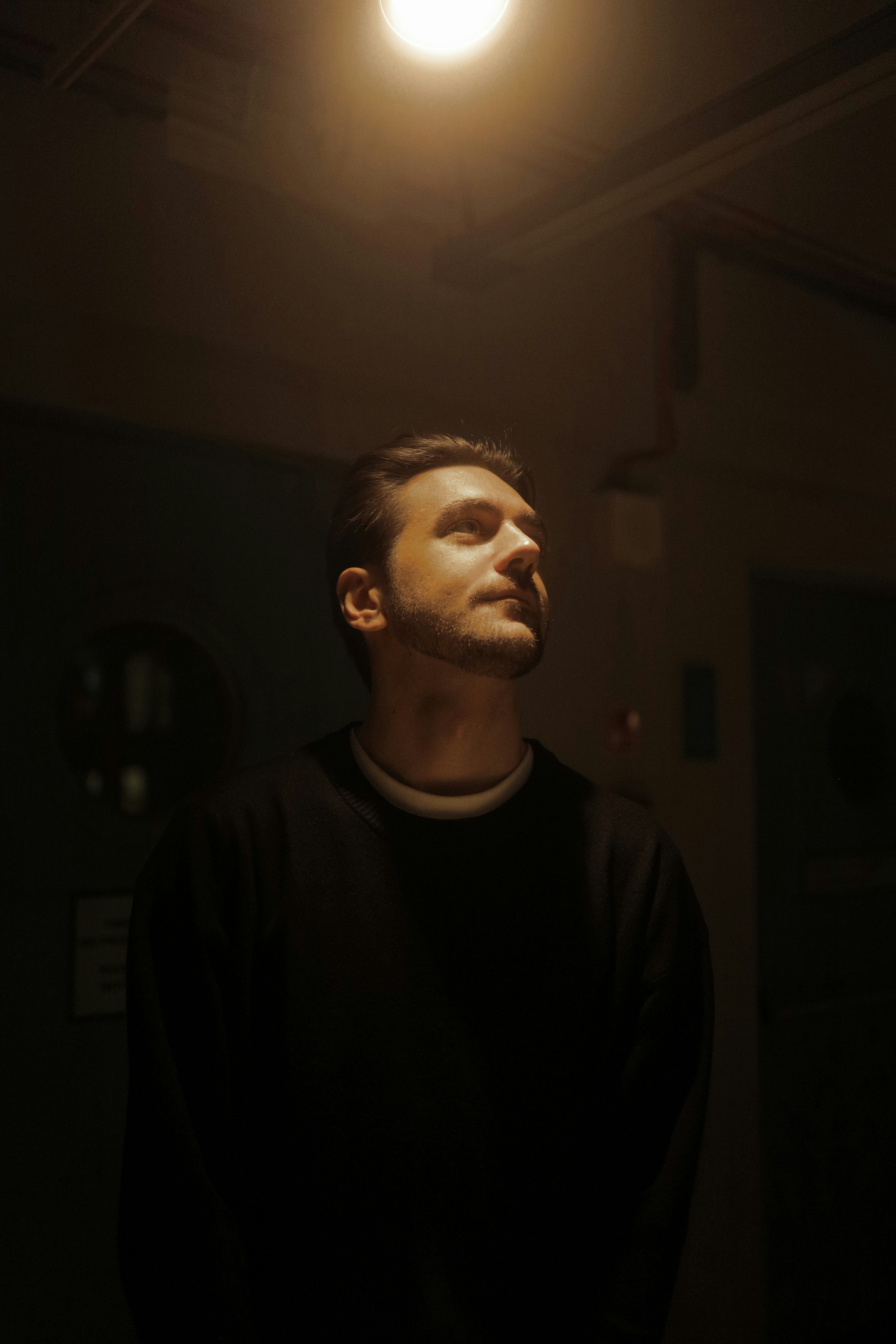 a man standing in a dark room under a light