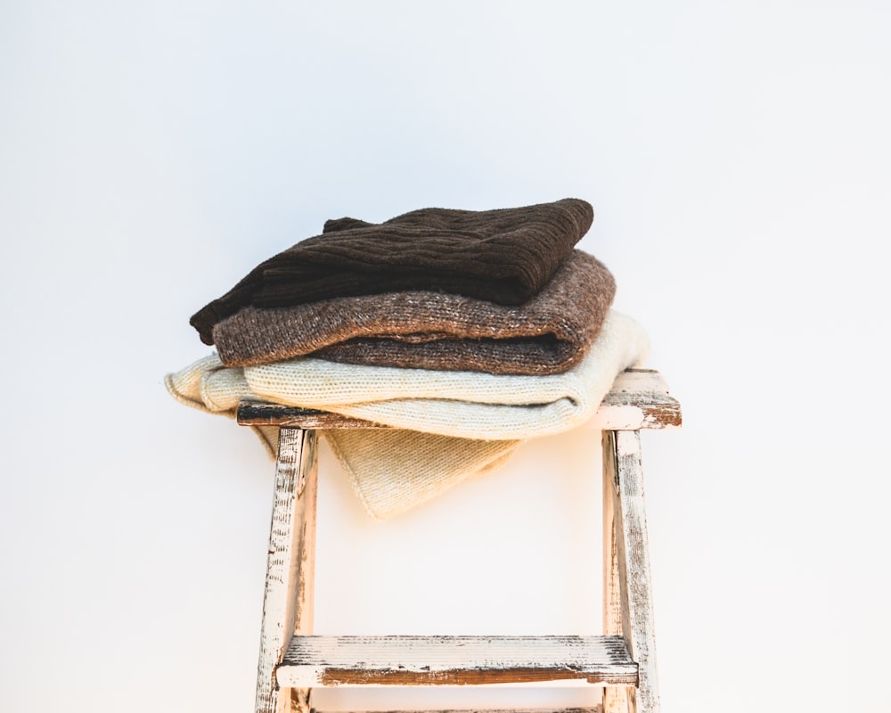 a stack of clothes sitting on top of a wooden stool