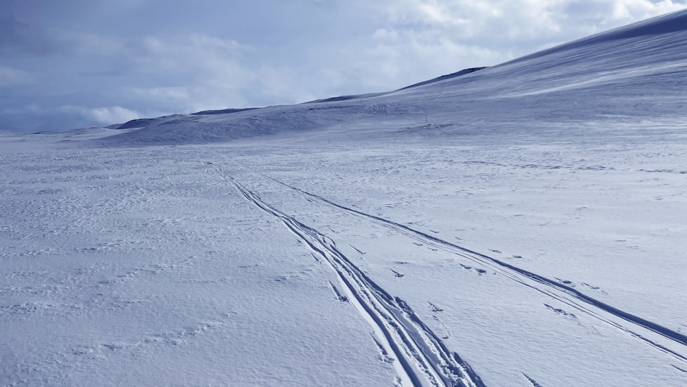 a couple of tracks in the snow near a hill