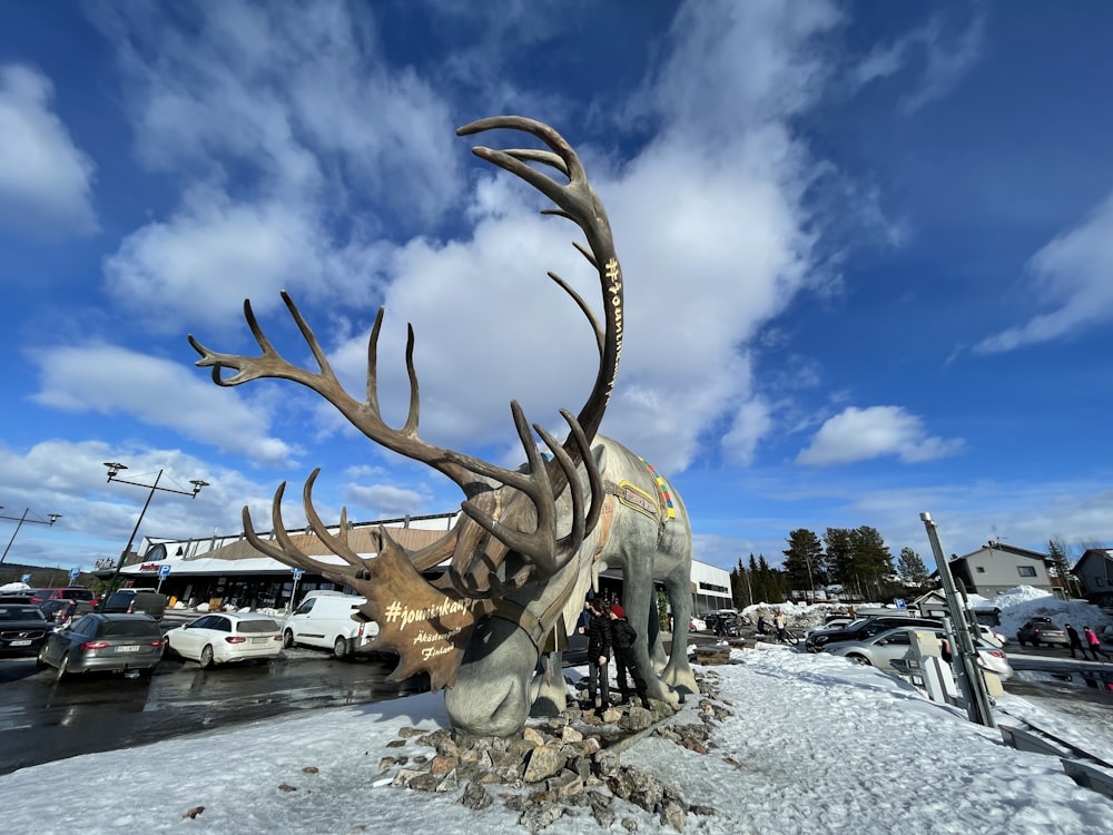 a statue of a deer with large antlers in a parking lot