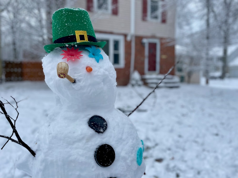 Un muñeco de nieve con un sombrero verde está en la nieve