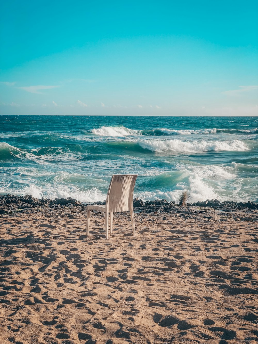 a white chair sitting on top of a sandy beach