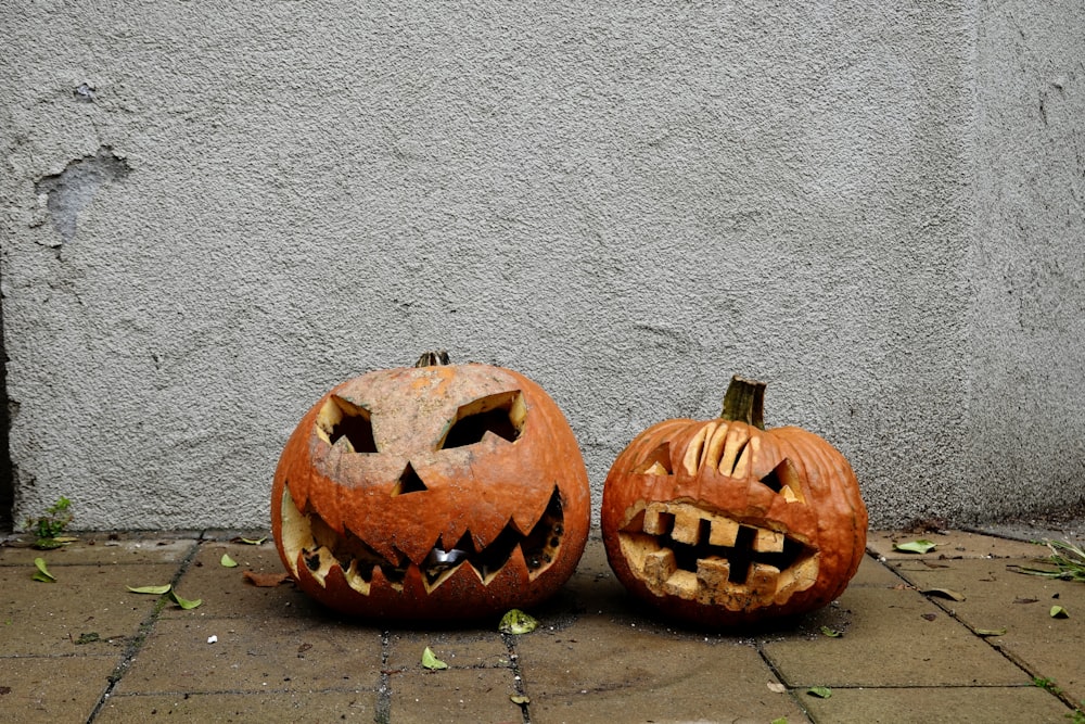 two carved pumpkins sitting next to each other on a sidewalk