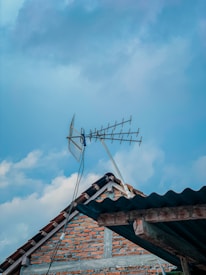 A technician installing a rooftop antenna in a suburban neighborhood during daylight.