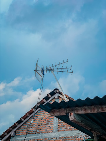 A technician installing a rooftop antenna in a suburban neighborhood during daylight.
