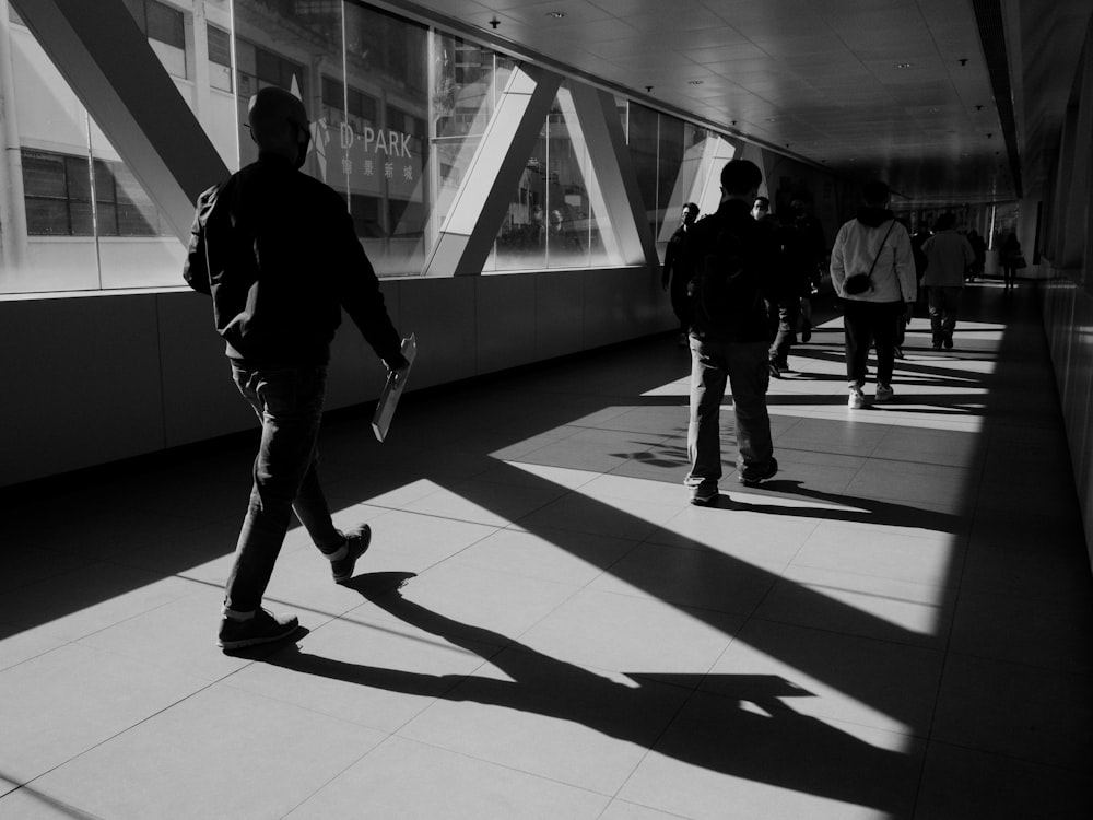 a black and white photo of people walking down a walkway