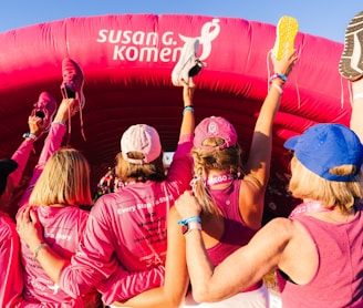 a group of women in pink shirts standing in front of a pink inflatable