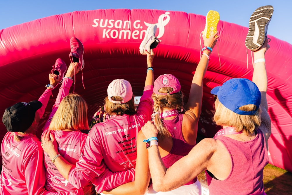 a group of women in pink shirts standing in front of a pink inflatable