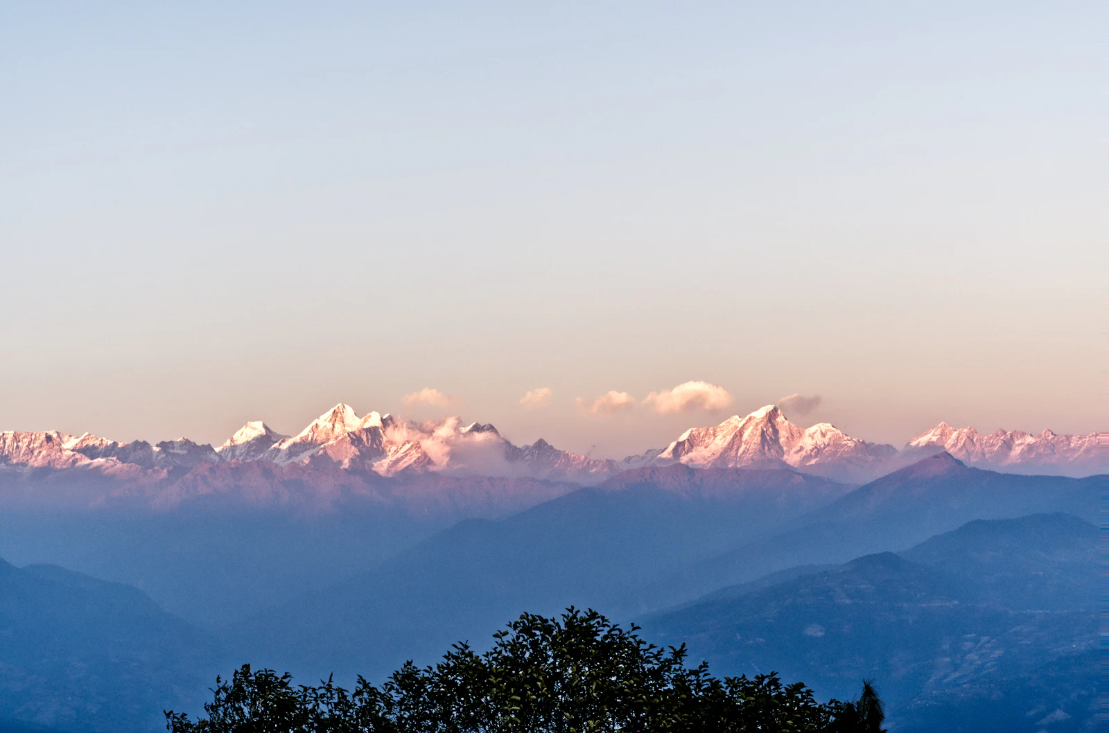 Himalayan peaks lit pink above layered blue ridges, seen from Nagarkot on the eastern rim of the Kathmandu Valley