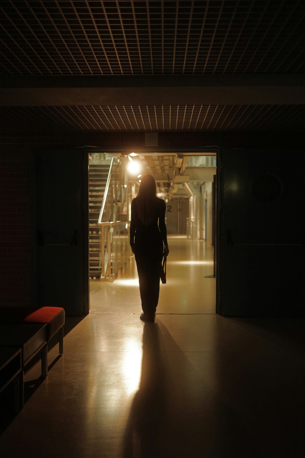a woman walking down a hallway in the dark