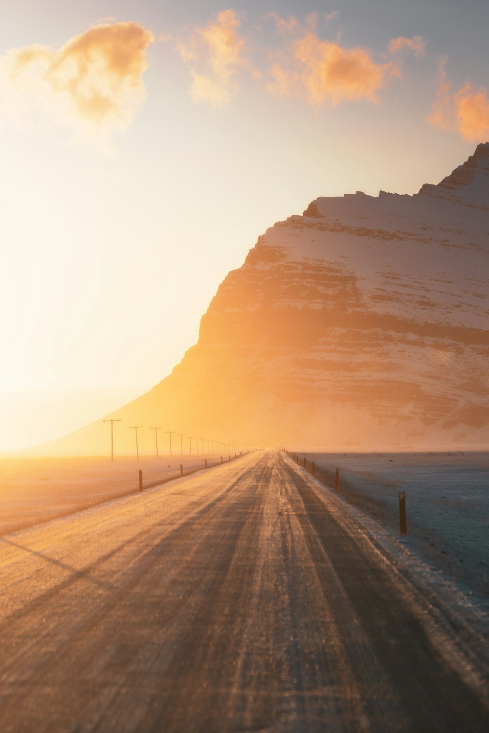 the sun is setting on a snowy road